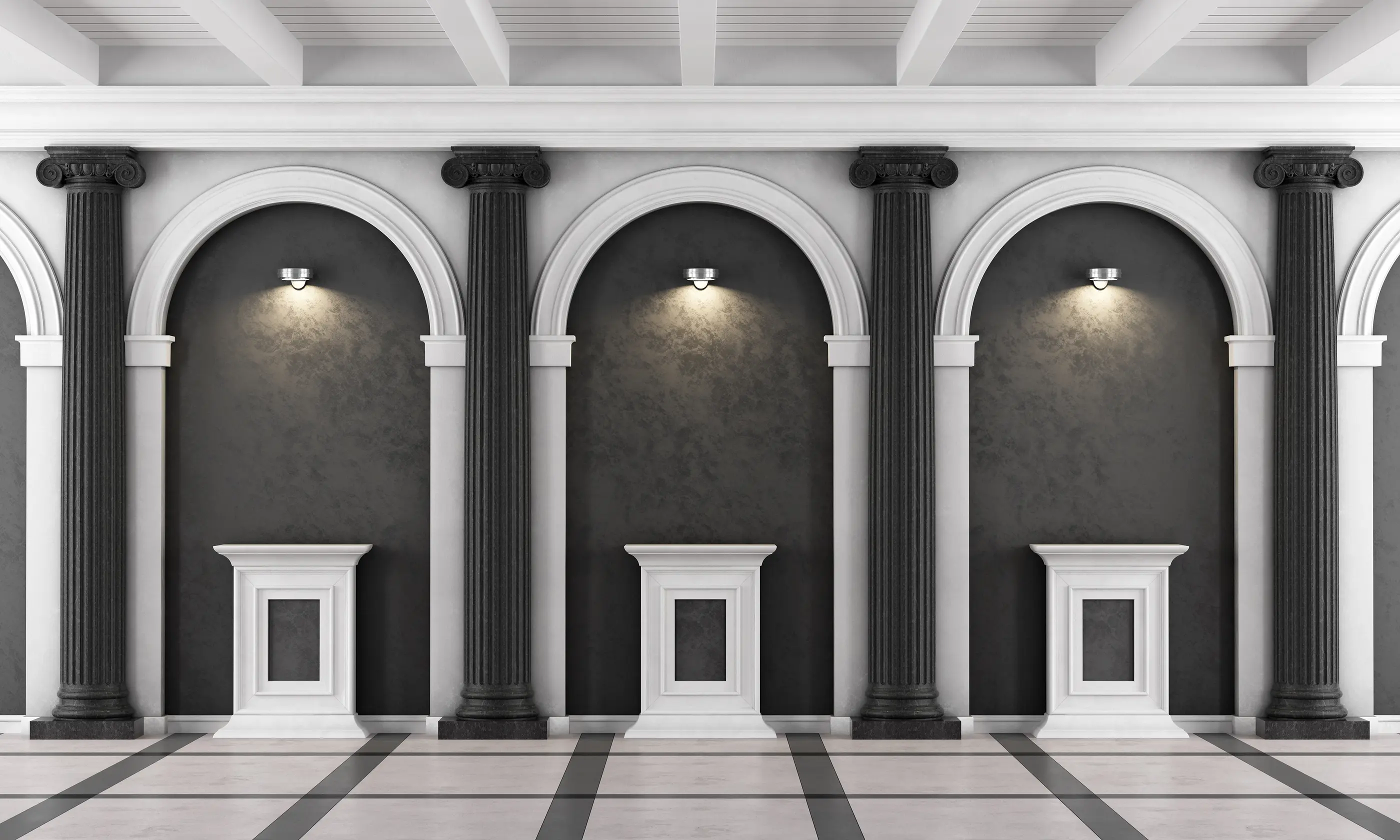A classical gallery wall featuring dark grey ionic columns, white arches, and matching pedestals illuminated by warm wall sconces