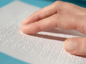 Hand moving over a text in braille language