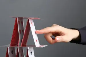 Woman,Destroying,House,Of,Playing,Cards,On,Grey,Background,,Closeup