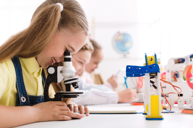 Stem Education. Girl Looking At Microscope With Robot Nearby