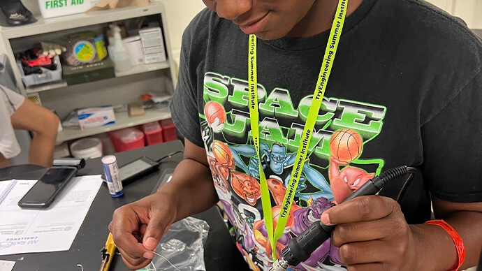 Kid wearing safety glasses and working with cables, engineering something in a lab with electricity