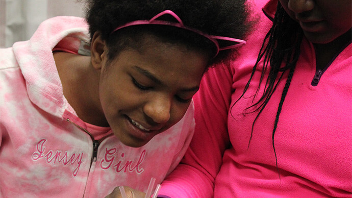 Two girls wearing pink, playing with scientific objects and learning