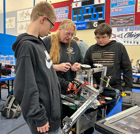 teacher instructing two students on engineering work