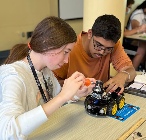 Two students collaborating to build a car