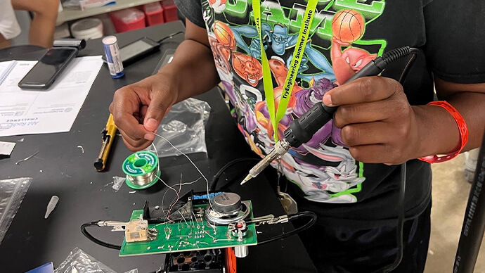 Kid wearing safety glasses and working with cables, engineering something in a lab with electricity