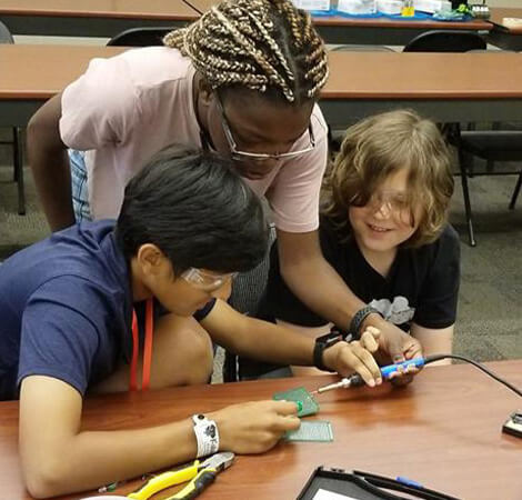 Teacher helping two young students how to the engineering design process